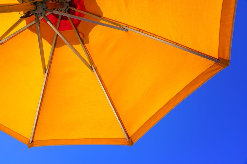 Looking up towards a blue sky under a yellow sun umbrella